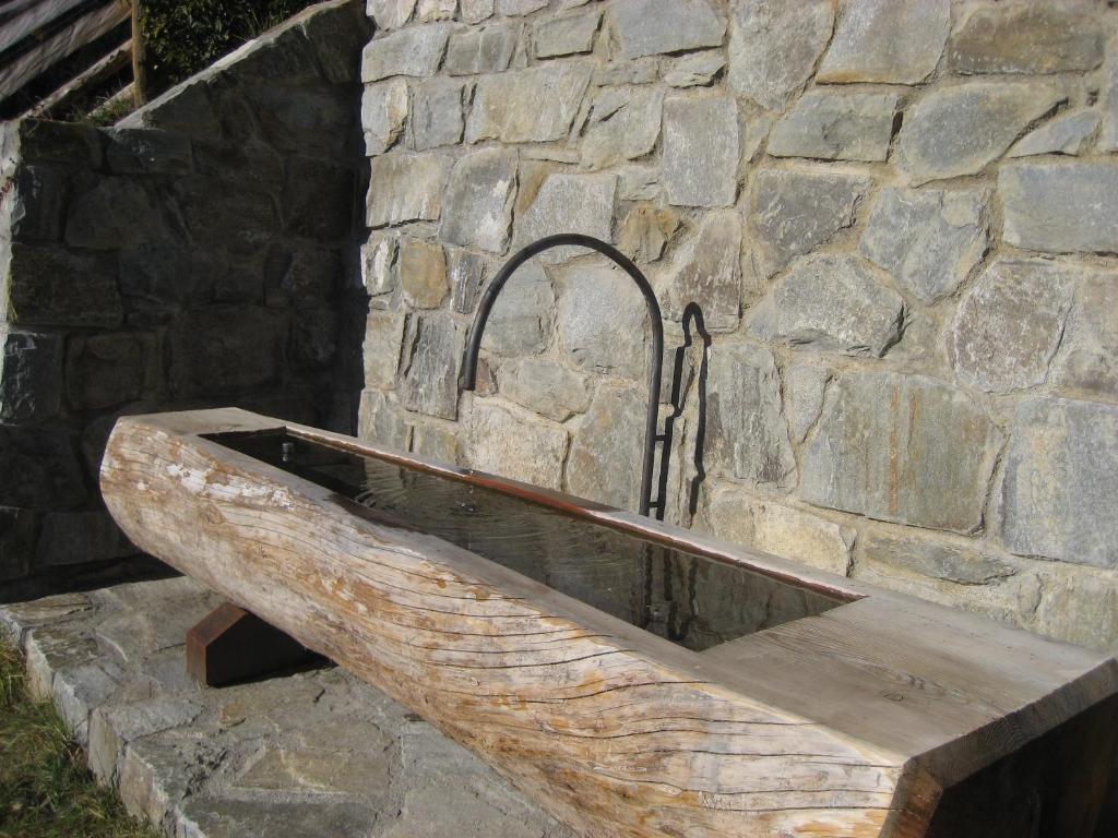 Hölzerner Brunnen an der Natursteinmauer
